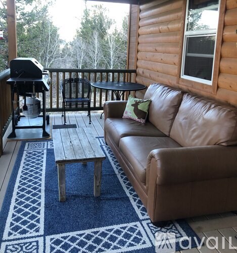 A tan couch is on a wooden deck with a blue rug.