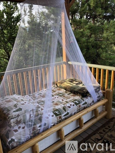 A mosquito net is draped over a bed on a wooden deck.