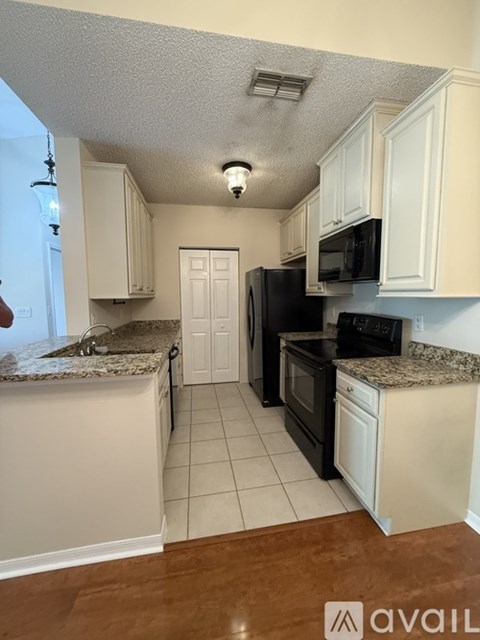 A kitchen with black appliances and white cabinets.