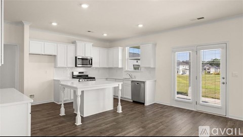 A kitchen with white cabinets and a white island with a microwave on top.