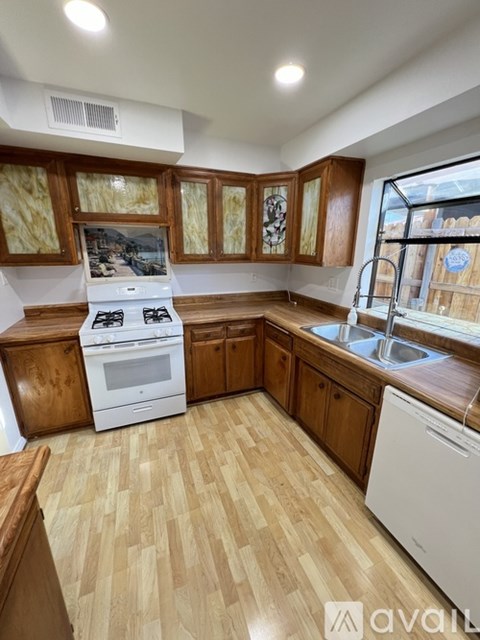 A kitchen with wooden cabinets and a white stove top oven.