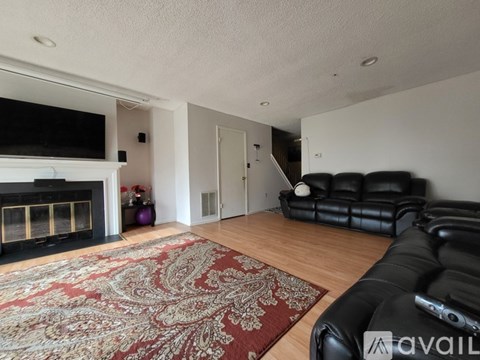 A living room with a black leather couch and a fireplace.