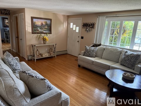 A living room with a grey couch and a painting on the wall.