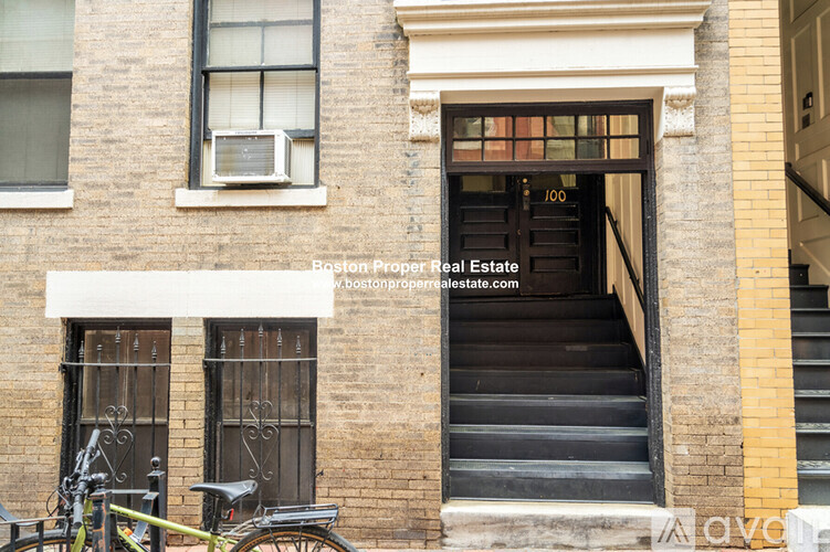 A bicycle is parked on the sidewalk in front of a brick building.