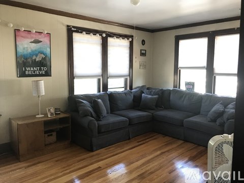 A living room with a grey couch and a poster that says "I want to believe".