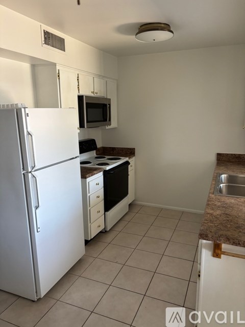 A kitchen with a white refrigerator, microwave, and stove.