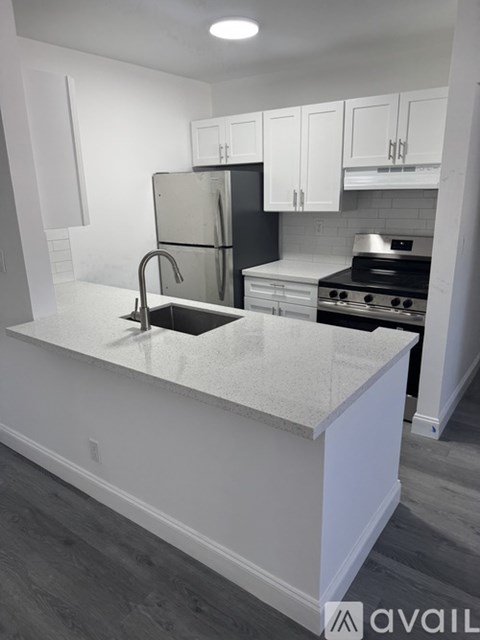 A kitchen with white cabinets and a black fridge.