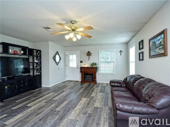 A living room with a brown leather couch and a wooden floor.