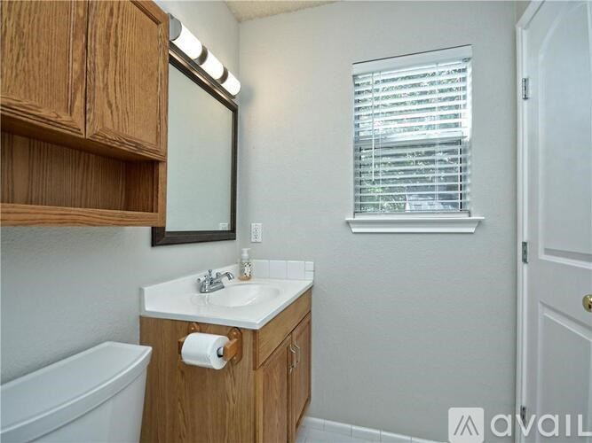 A bathroom with a wooden cabinet, a white sink, and a window with blinds.