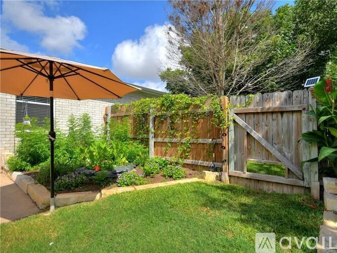 A backyard with a wooden fence and a small tree.