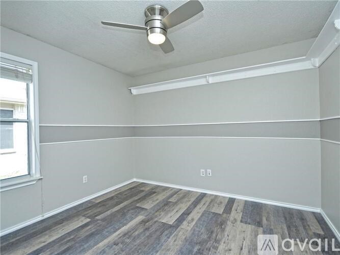 A room with a ceiling fan and wooden flooring.