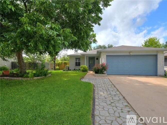 A house with a driveway and a tree in front.