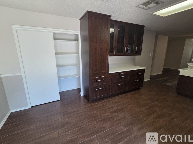 A patio with chairs and umbrellas is surrounded by a fence and greenery.