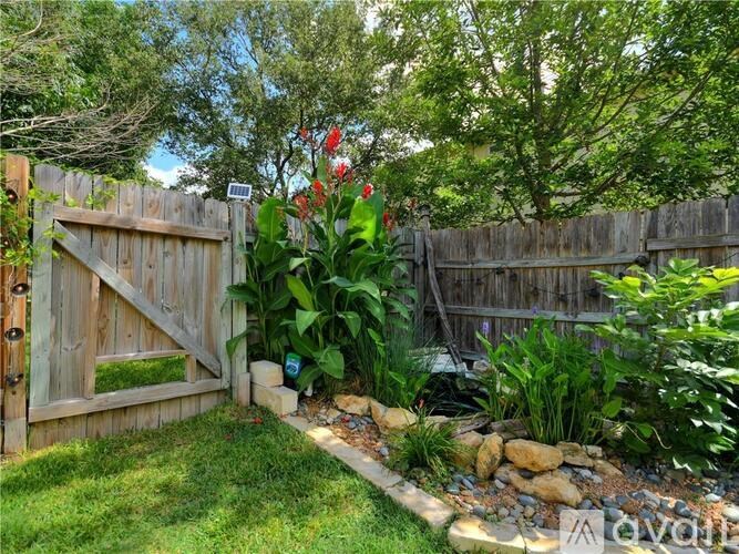 A garden with a wooden gate and a stone path.