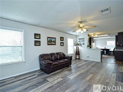 A living room with a brown leather couch and a ceiling fan.