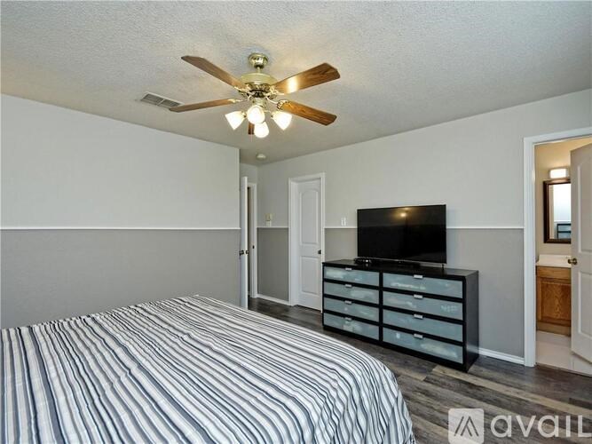 A bedroom with a bed, a television, and a ceiling fan.