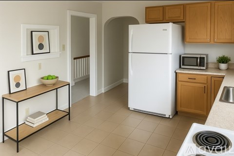 A white refrigerator in a kitchen with wooden cabinets and a black stove.