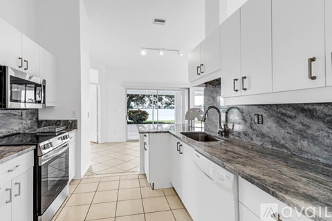 A modern kitchen with white cabinets and a marble countertop.