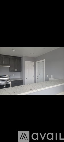 A modern kitchen with dark cabinets and a white countertop.