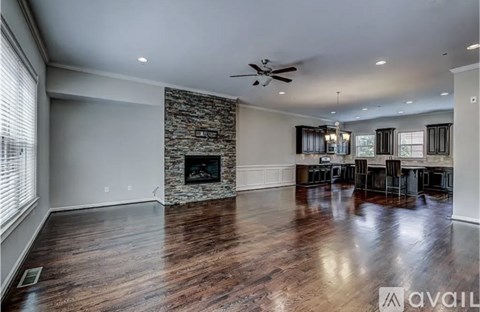 A spacious living room with a stone fireplace and hardwood floors.