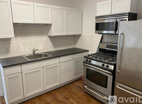 A kitchen with white cabinets and a black countertop.