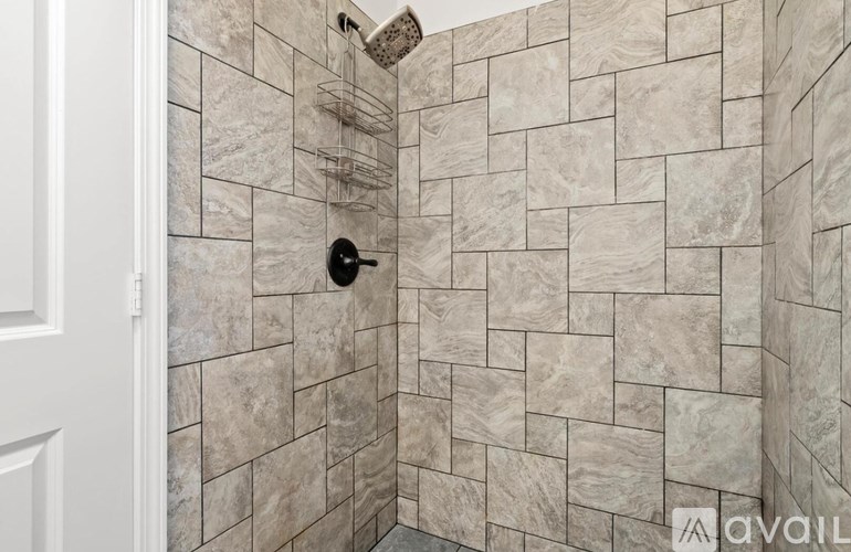 A tiled shower with a black drain plug.