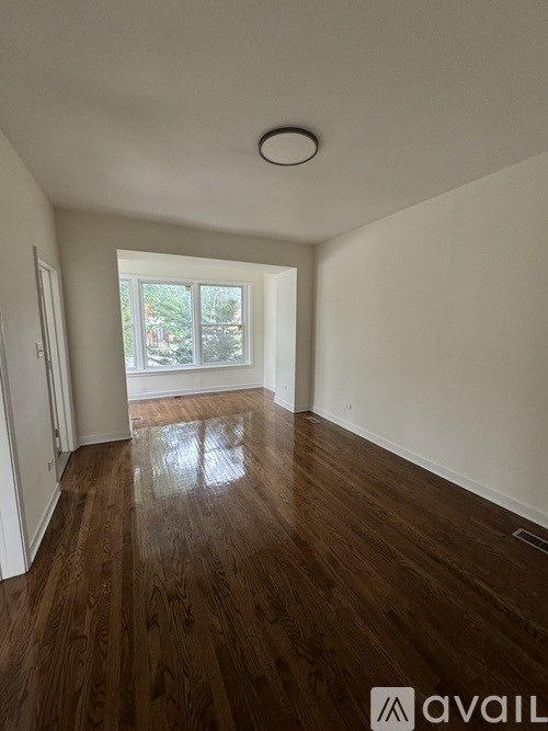 A room with wooden floors and a window letting in light.