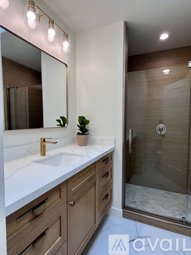 A bathroom with a sink, mirror, and a plant.