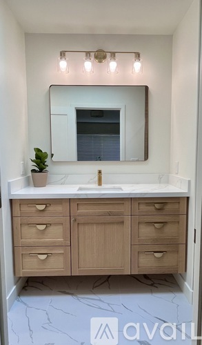 A bathroom vanity with a marble floor and a mirror above the sink.