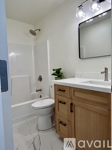 A bathroom with a toilet, sink, and mirror.