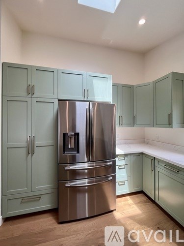 A kitchen with a stainless steel refrigerator and cabinets.
