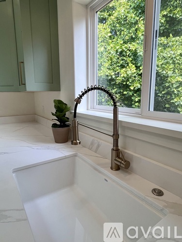 A bathroom with a white tub and a window with a view of trees.
