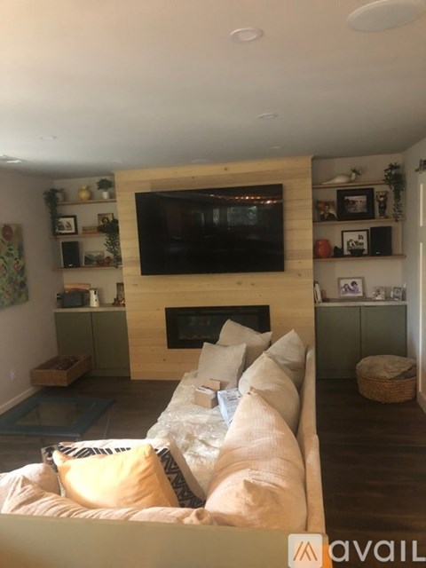 A living room with a fireplace and a television mounted above it.