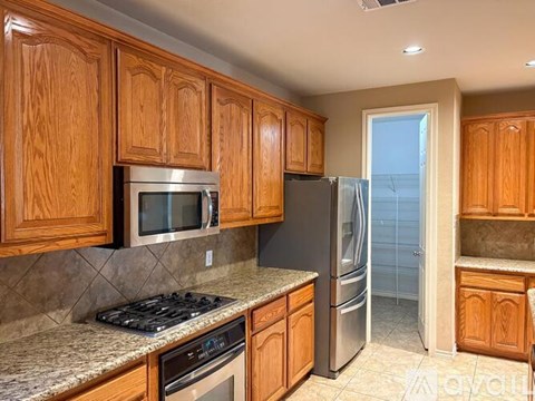 A kitchen with wooden cabinets and a black refrigerator.