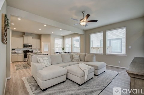 A living room with a large sectional sofa and a ceiling fan.