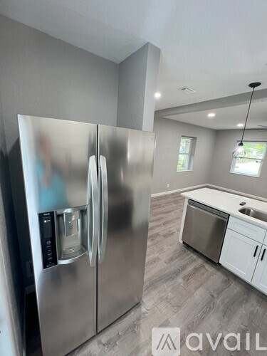 A modern kitchen with a stainless steel refrigerator and white cabinets.