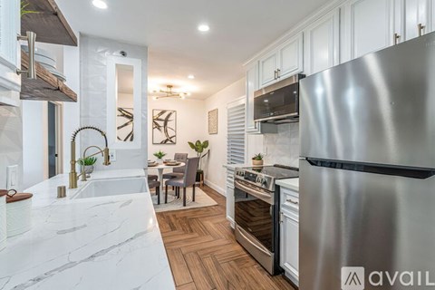 A modern kitchen with a stainless steel refrigerator and wooden flooring.