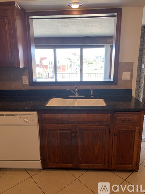 A kitchen with a white dishwasher and wooden cabinets.