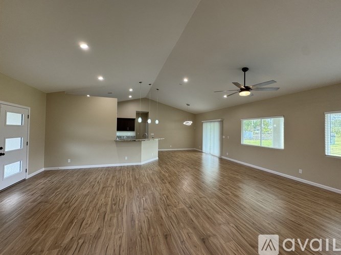 A spacious room with wooden floors and a ceiling fan.