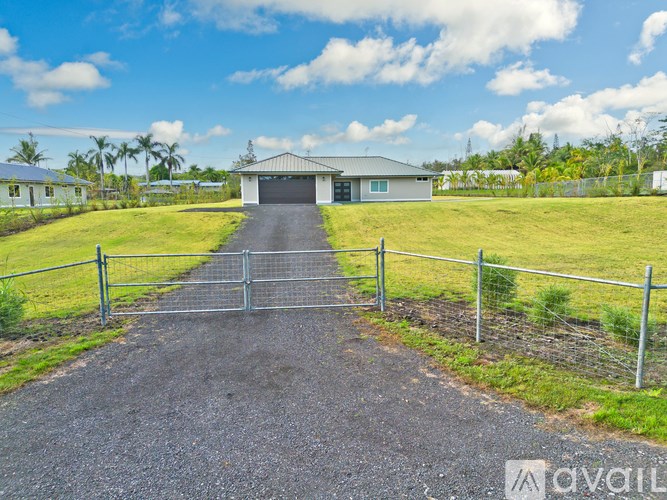A gravel driveway leads to a house with a metal fence on either side.