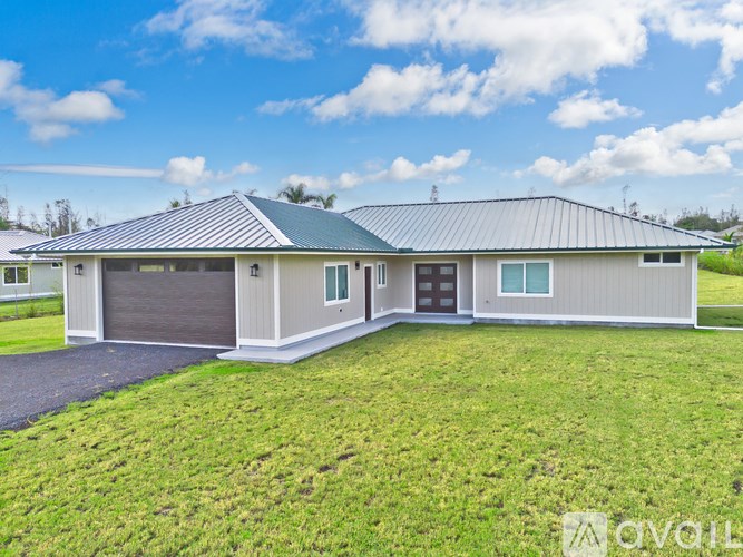 A modern house with a grey roof and a green lawn in front.