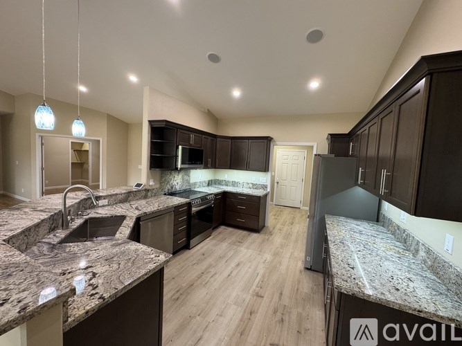 A modern kitchen with granite countertops and dark wood cabinets.