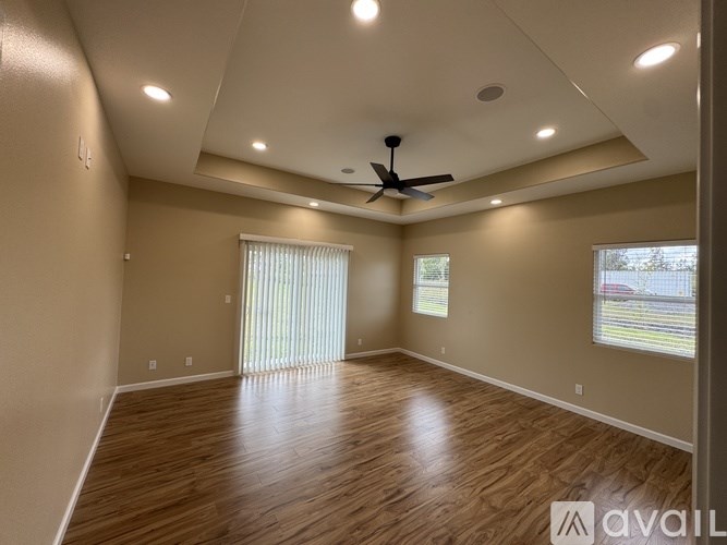 A spacious room with wooden flooring and a ceiling fan.