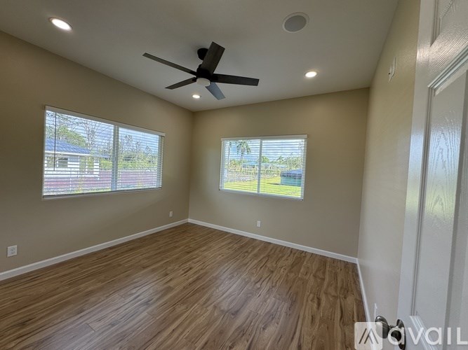 A room with a ceiling fan and two windows.