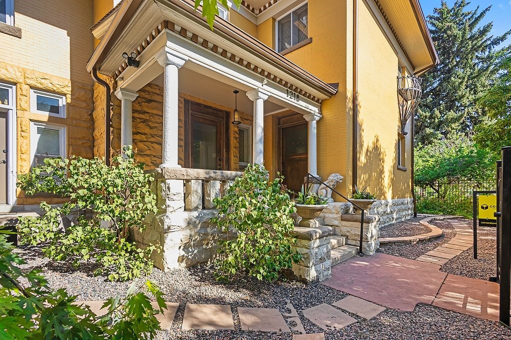 A yellow house with a porch and a garden in front.