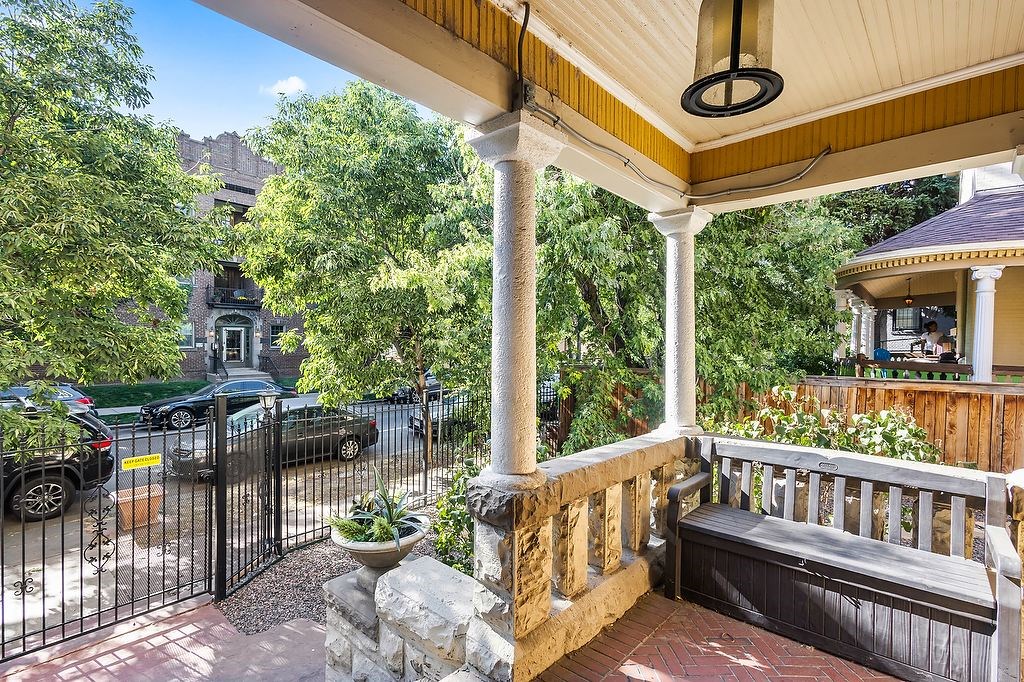 A porch with a bench and pillars with a view of a street.