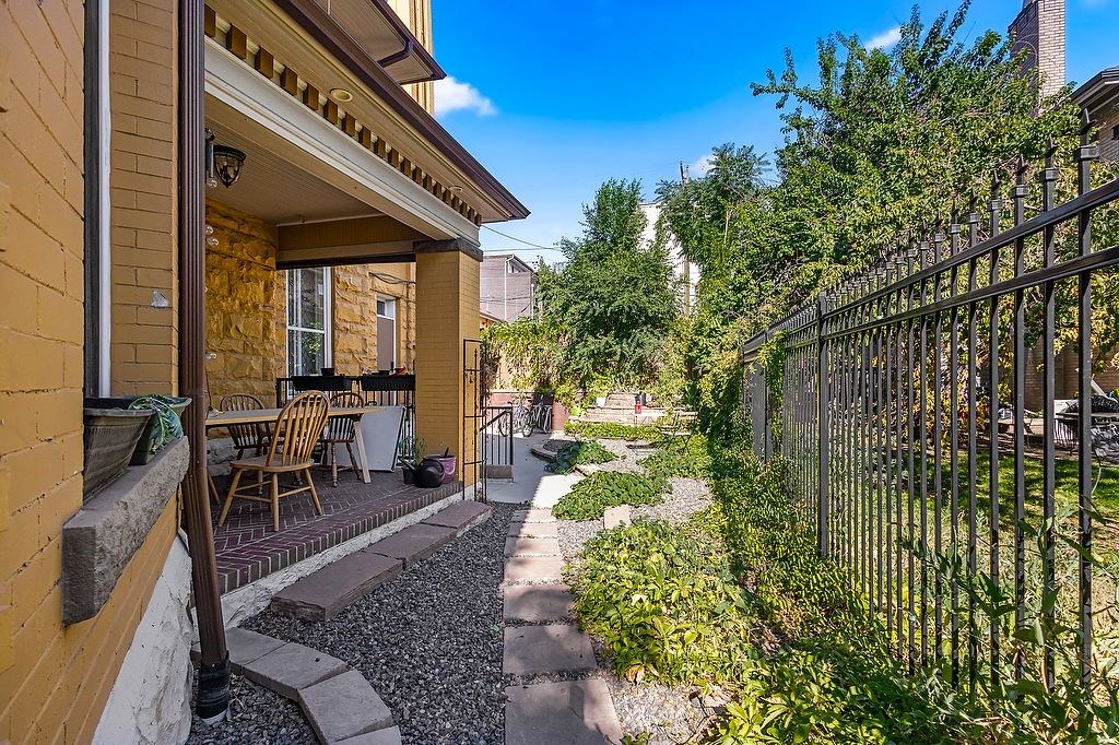 A yellow house with a black fence and a gravel path leading to the front door.