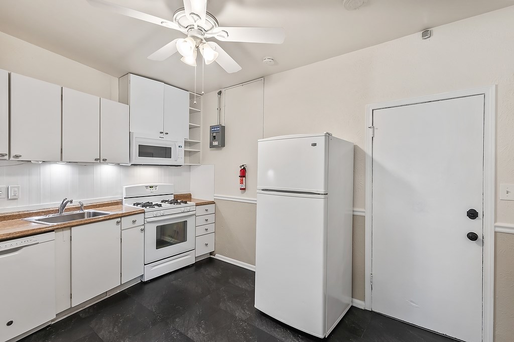 A white kitchen with a refrigerator, oven, and microwave.