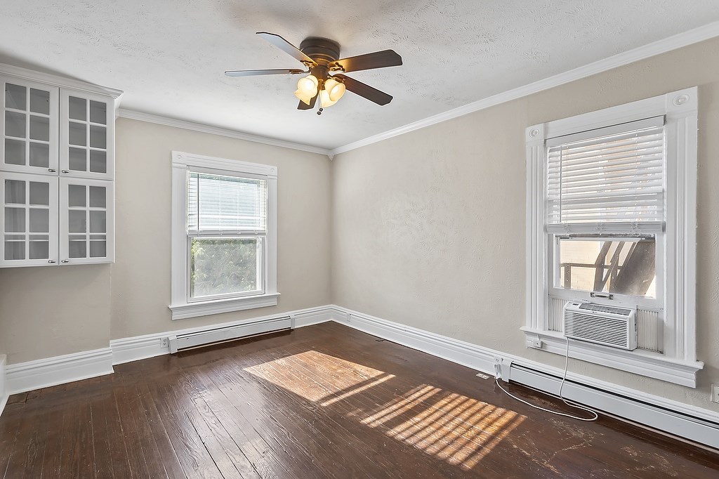 A room with a ceiling fan and two windows.