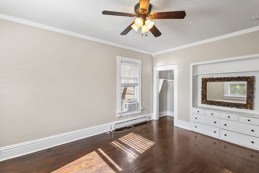 A room with a ceiling fan and a wooden floor.